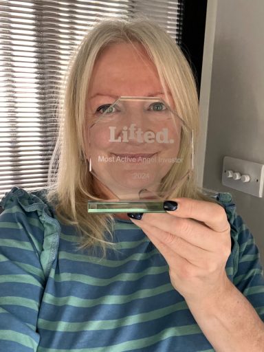 A white woman with blonde hair holding a glass trophy in front of her face, reading Lifted Ventures, Most Active Angel Investor